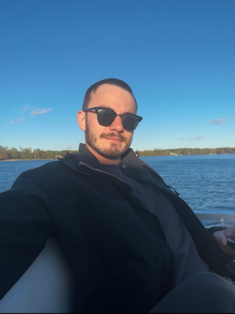 Jaden Smith, founder of Boylan Generators, sitting in front of a lake wearing sunglasses and holding a cup.